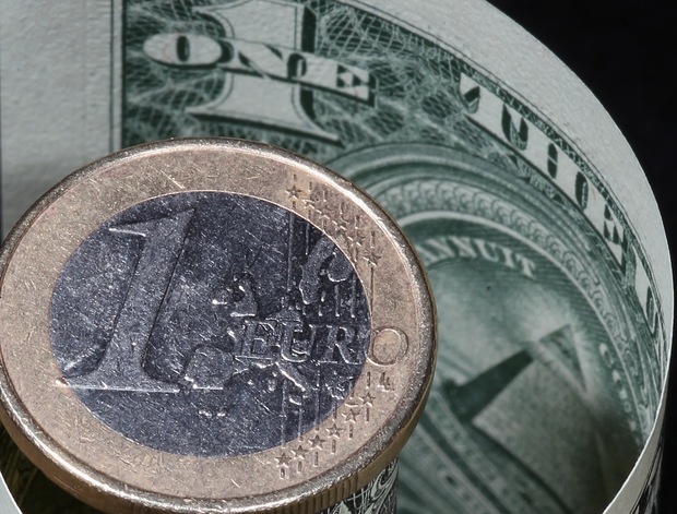 A euro coin rest on top of a dollar bill. Photo by: Dan Kitwood/Getty Images.